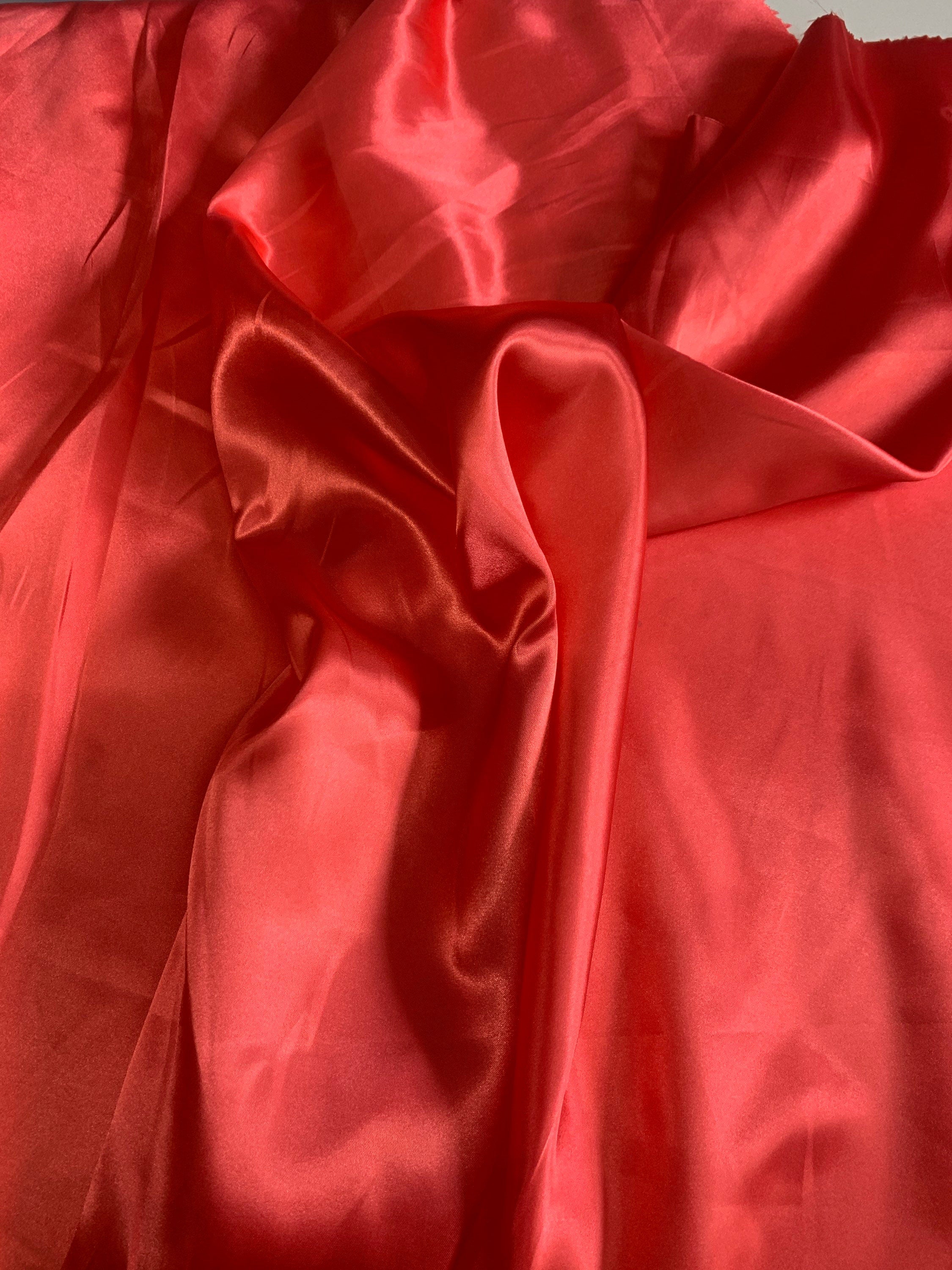 Red charmeuse satin 100% polyester color is dark coral. Lustrous , smooth fabric, shiny on front and matte in back