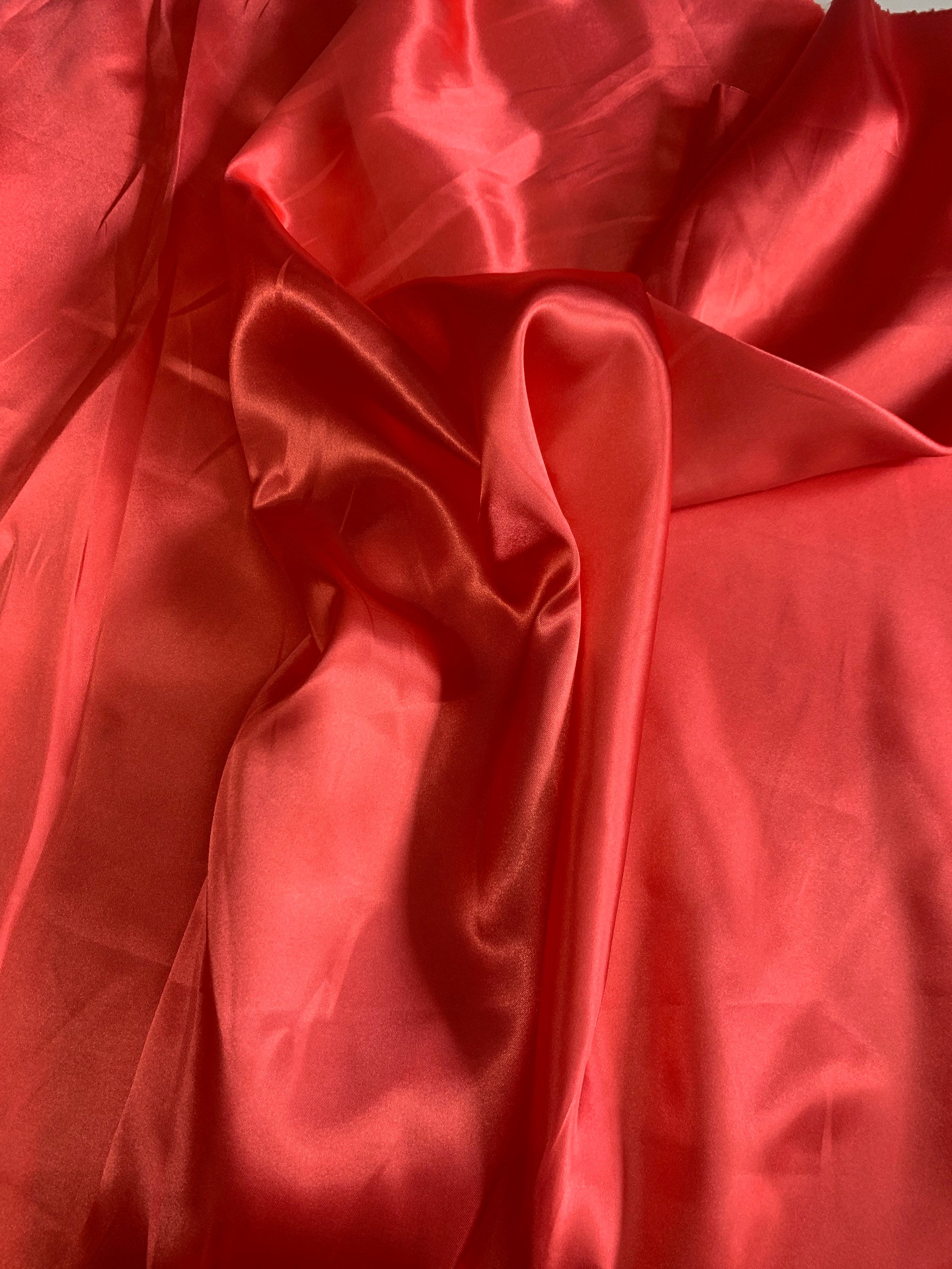 Red charmeuse satin 100% polyester color is dark coral. Lustrous , smooth fabric, shiny on front and matte in back