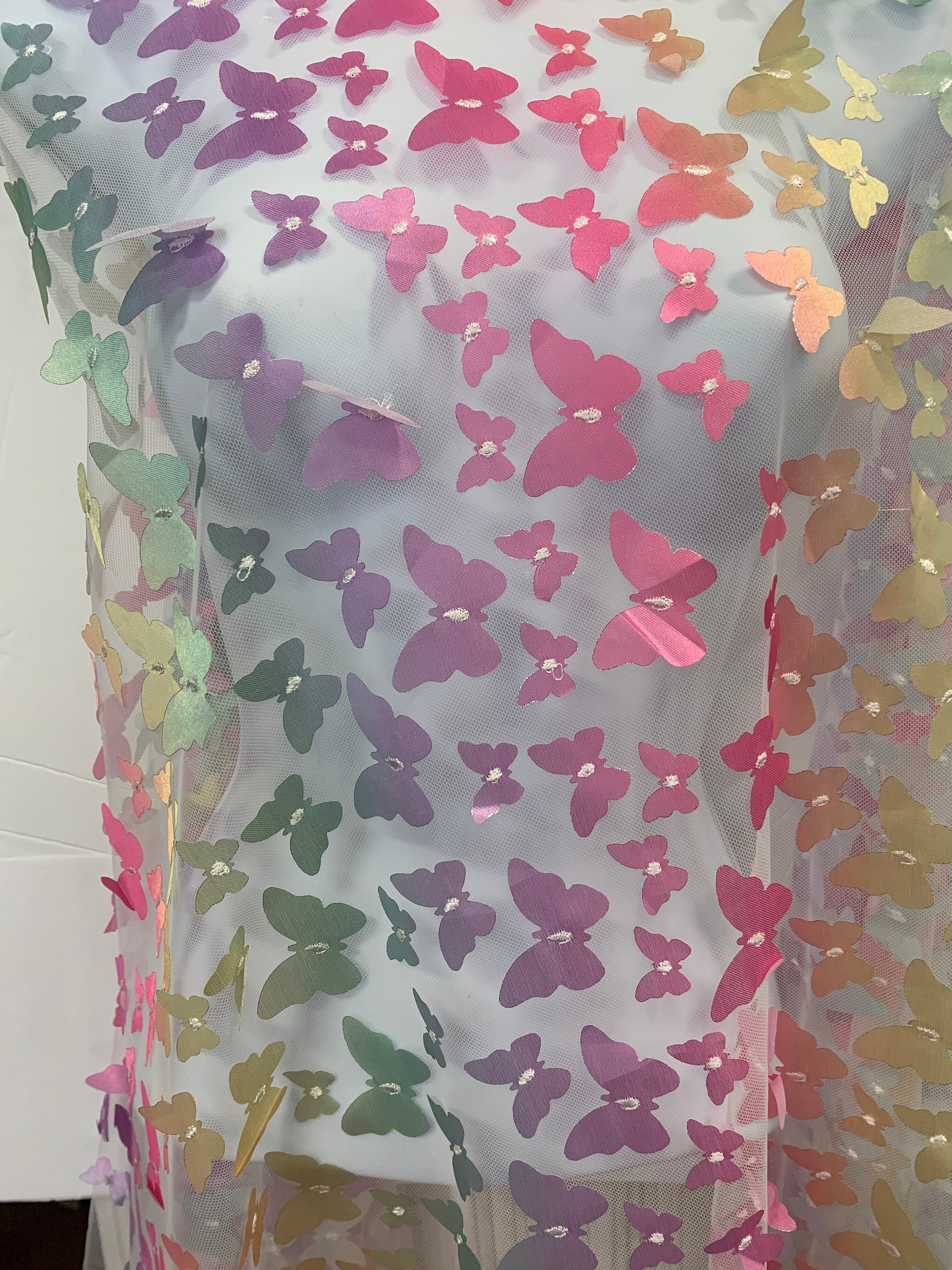lace Butterfly on mesh design fabric. color rainbow. 60 inch width,fabric has 5 inch plain salvage on each side. butterfly are is 50 inches.