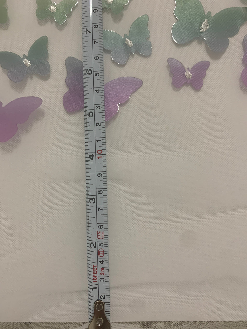 lace Butterfly on mesh design fabric. color rainbow. 60 inch width,fabric has 5 inch plain salvage on each side. butterfly are is 50 inches.