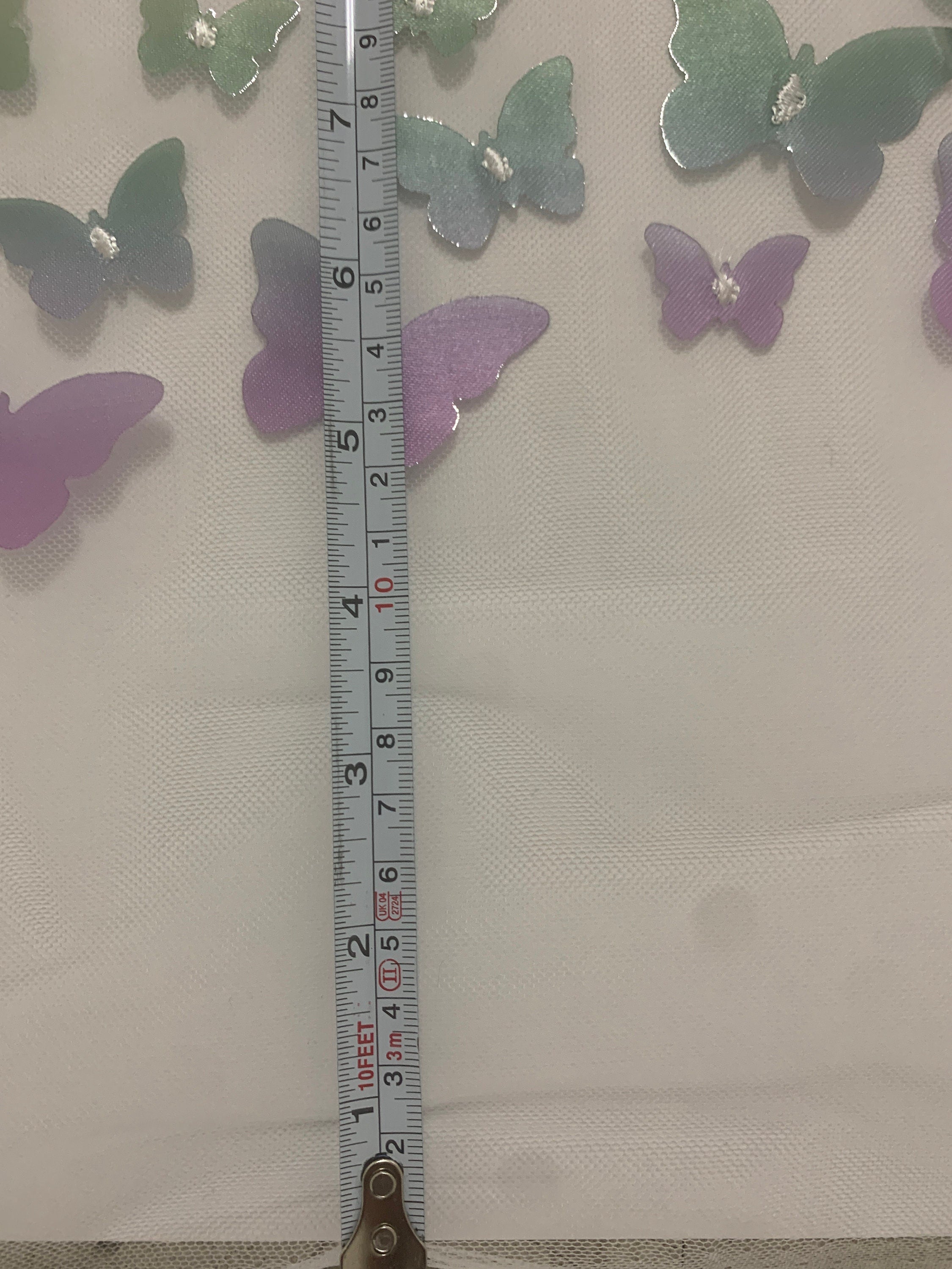 lace Butterfly on mesh design fabric. color rainbow. 60 inch width,fabric has 5 inch plain salvage on each side. butterfly are is 50 inches.