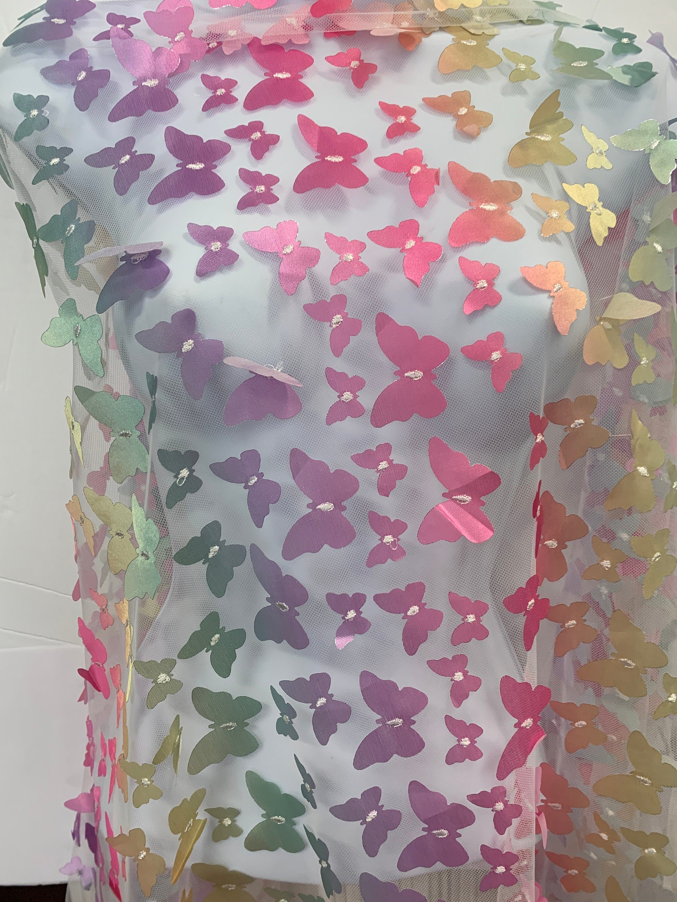 lace Butterfly on mesh design fabric. color rainbow. 60 inch width,fabric has 5 inch plain salvage on each side. butterfly are is 50 inches.