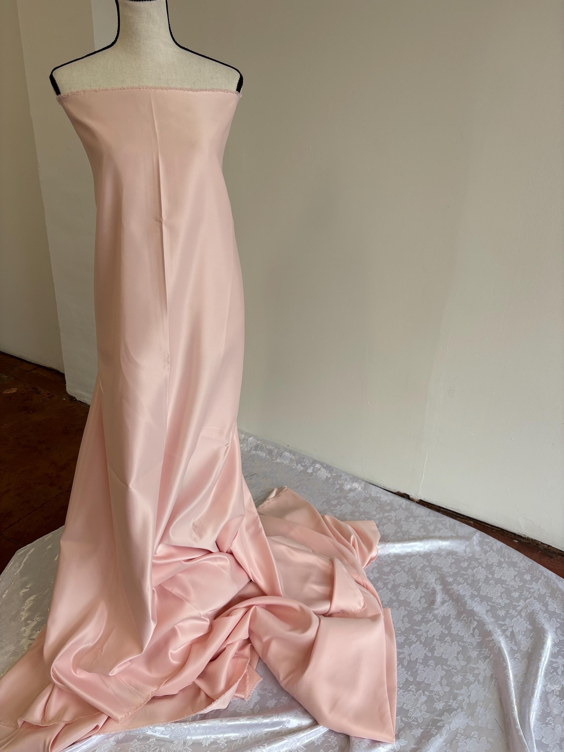 Light pink dull satin fabric, 58/60” wide, made of polyester – an excellent choice for gowns.