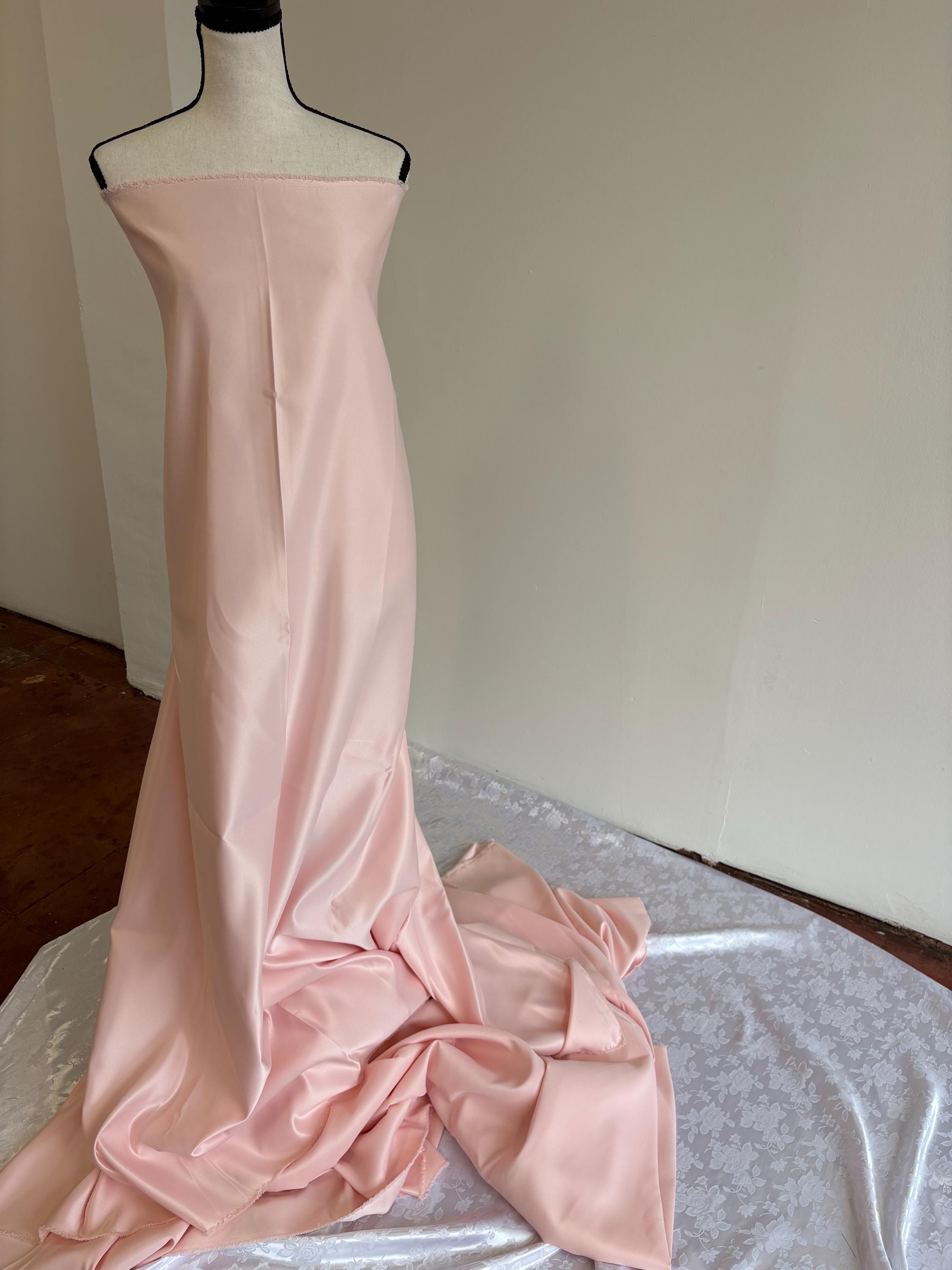 Light pink dull satin fabric, 58/60” wide, made of polyester – an excellent choice for gowns.