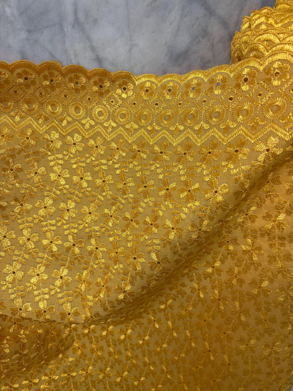 Eyelet fabric made of poly-cotton with all-over embroidery and double scalloped edges for a delicate finish. color Gold design # 2